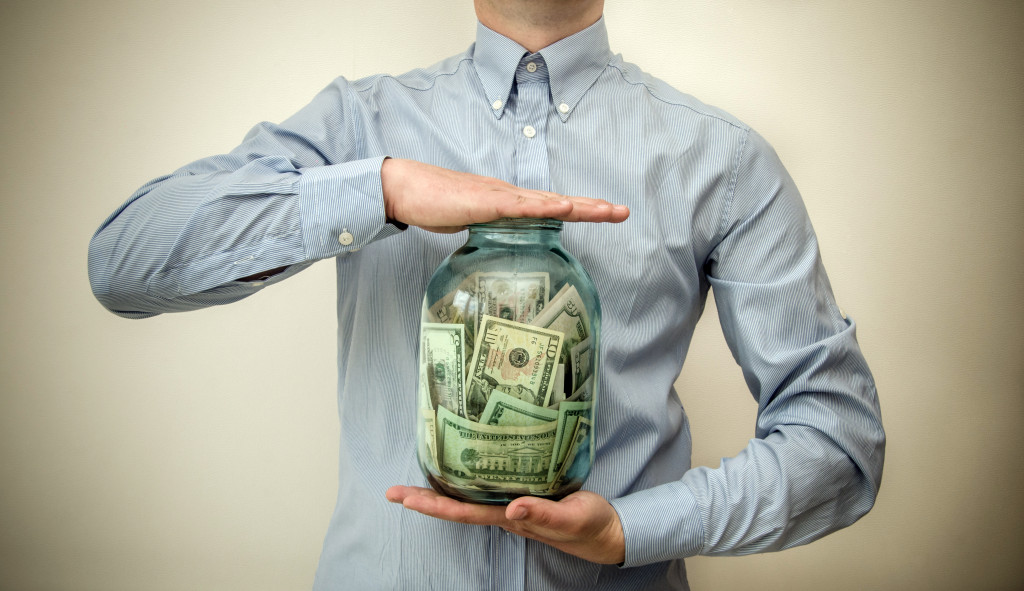 Man holding a jar filled with cash