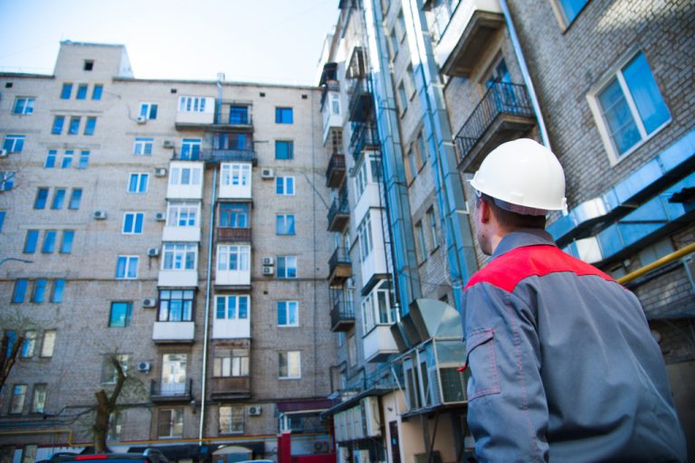 man in hard hat looking at an old building